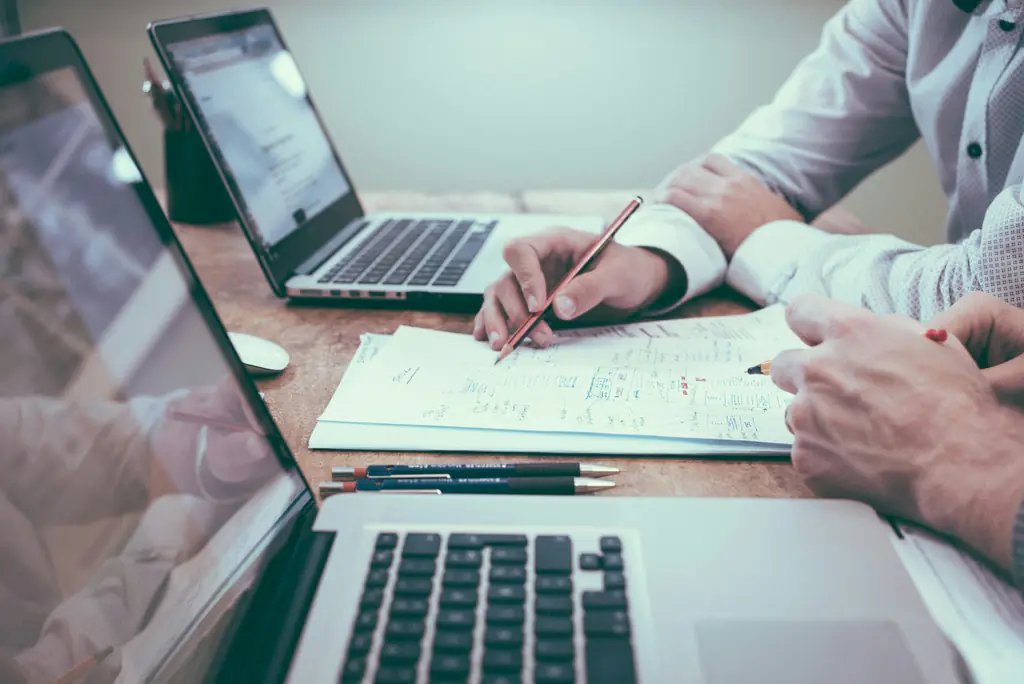 Dos personas revisando cuentas con un portátil y papeles